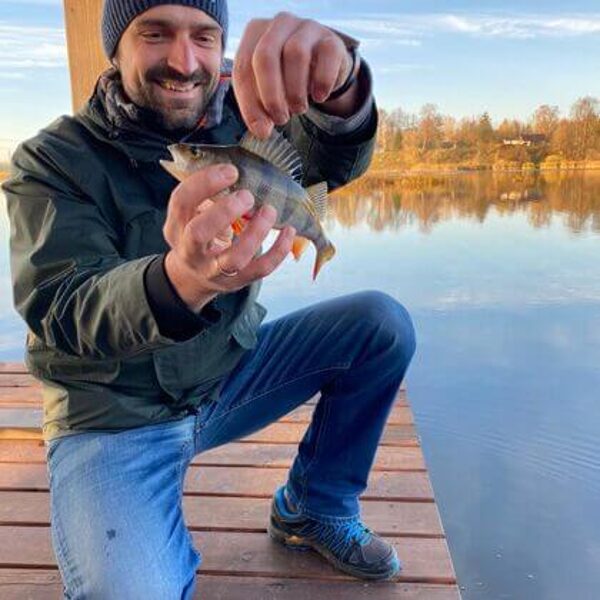 Vīrietis ar zivi pie Daugavas uz pontona.