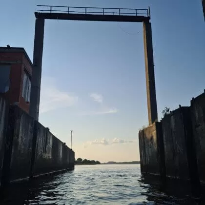 Skats no ūdens uz industriāliem vārtiem.