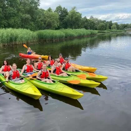 Grupa cilvēku kajakos Daugavā.